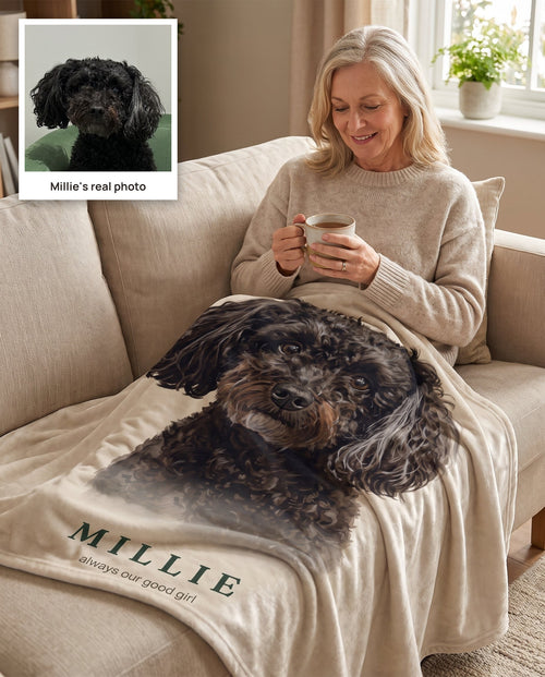 A woman on her couch under a throw printed with a portrait of Millie, her black curly-coated dog, with Millie's real photo shown in the corner.